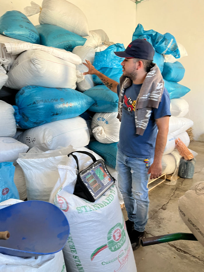 Person working with bags of coffee and a digital scale in an industrial setting