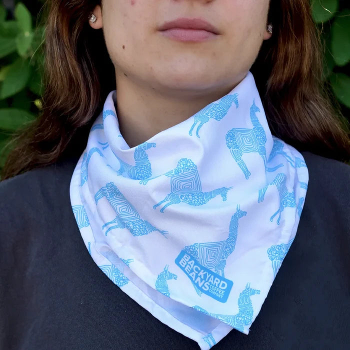 Person wearing a white bandana with blue llama pattern set against a blurred green background.