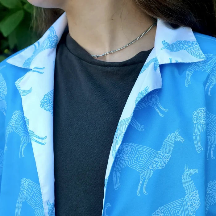 Person wearing a blue shirt with white llama pattern over a black shirt.