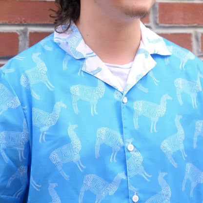 Person wearing a blue shirt with llama pattern in front of a brick wall