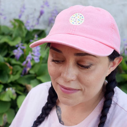 Image of woman wearing coral hat with embroidered sprinkle cookie