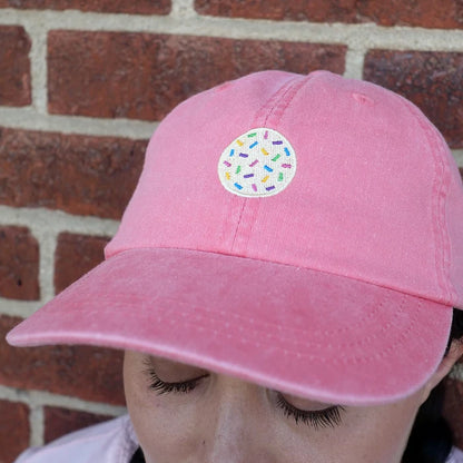 Image of front of coral dad hat with embroidered sprinkle cookie