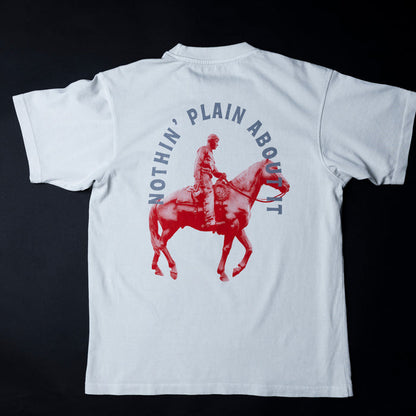 off-White short-sleeve T-shirt shown from the back against a black background, featuring a large red graphic of a cowboy riding a horse with the text 'NOTHIN' PLAIN ABOUT IT' in blue arched above.